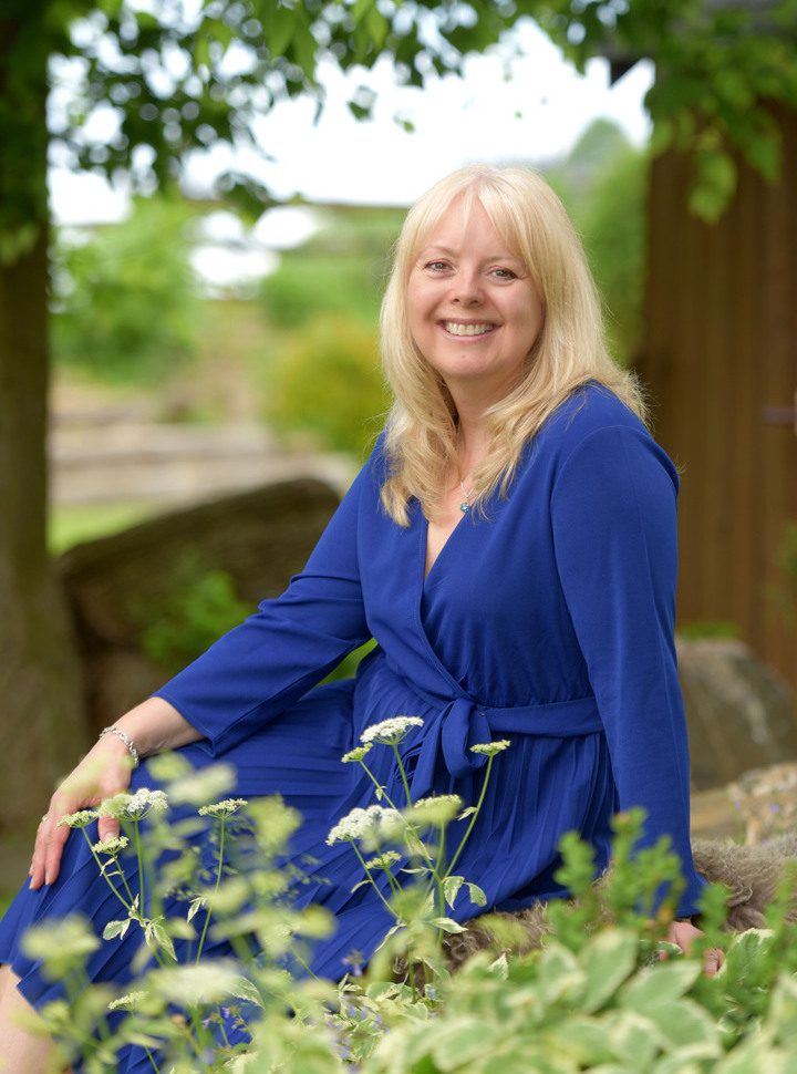 A woman in blue dress sitting on a bench.