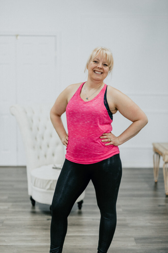 A woman in pink shirt and black pants standing.